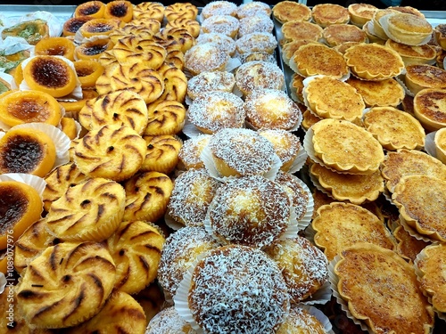 A vibrant display of various Portuguese pastries including custard tarts, coconut sweets, and puff pastries. Perfectly arranged on a bakery shelf, they evoke sweetness and indulgence.