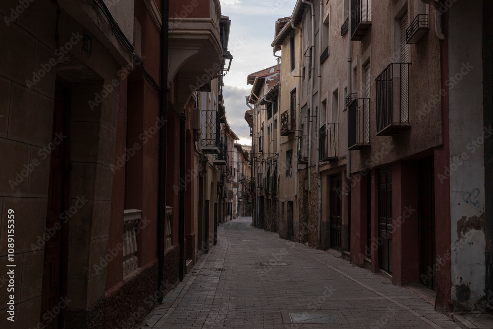 Narrow and quiet cobblestone street lined with traditional buildings in a historic European village at dusk Narrow and quiet cobblestone street lined with traditional buildings in a historic European village at dusk