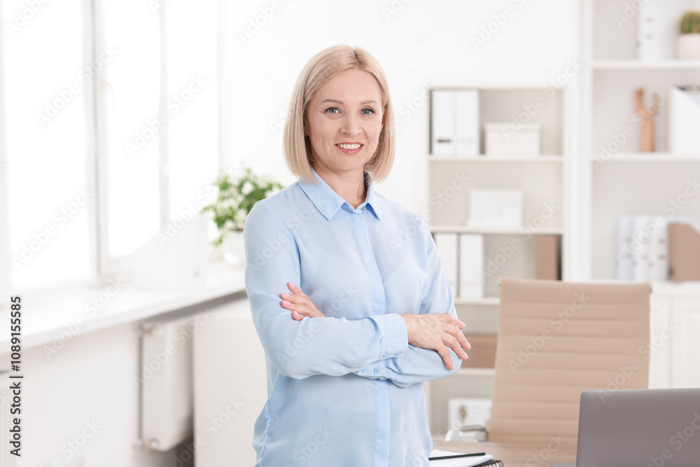 Portrait of smiling middle aged woman with crossed arms in office Portrait of smiling middle aged woman with crossed arms in office