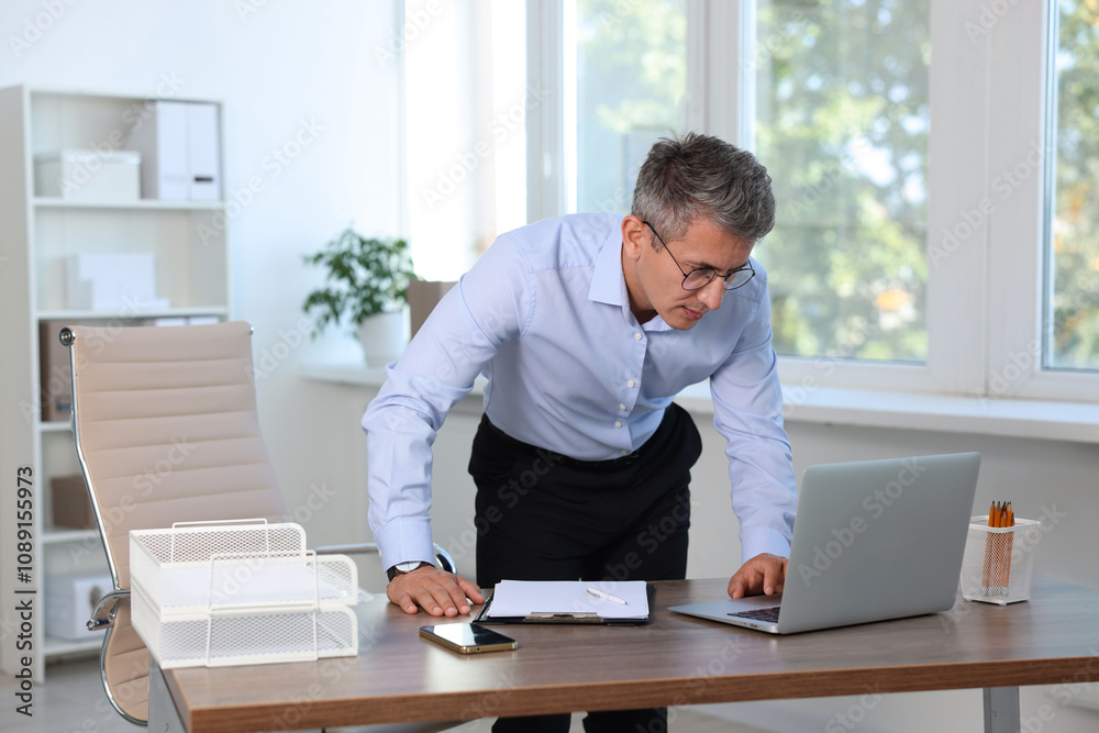 Middle aged man working with laptop in office Middle aged man working with laptop in office