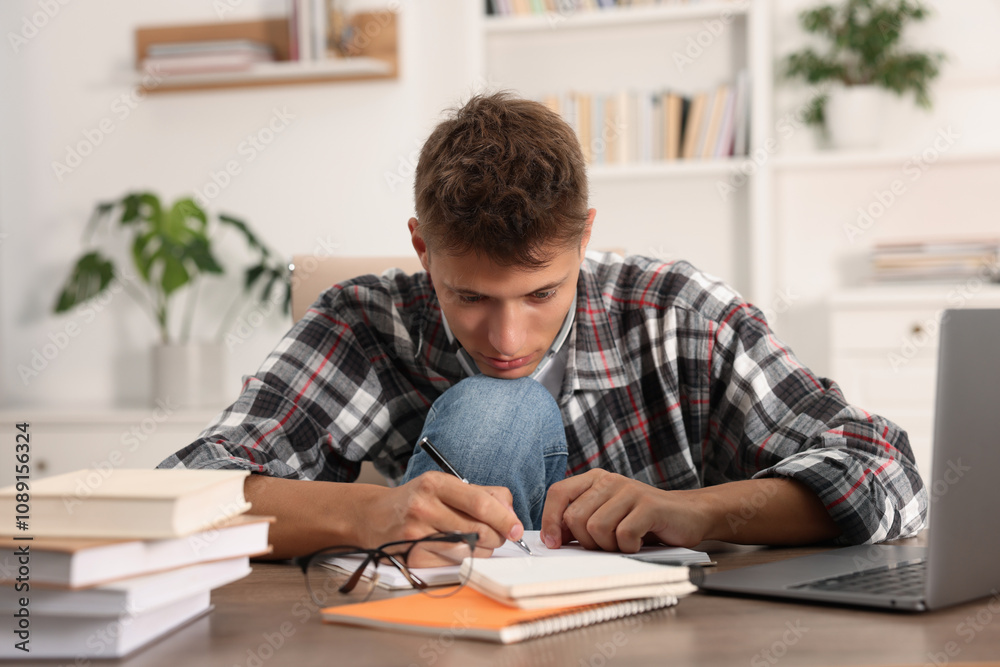 Student taking notes while studying at table indoors Student taking notes while studying at table indoors