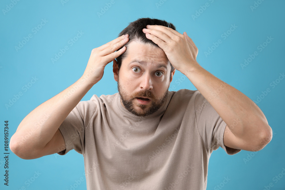 Man with hair loss problem on light blue background Man with hair loss problem on light blue background