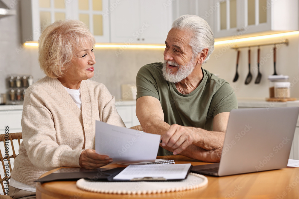 Pension savings. Senior couple planning budget at wooden table indoors Pension savings. Senior couple planning budget at wooden table indoors