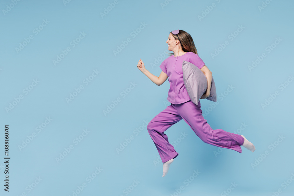 Full body calm happy young woman wear purple pyjamas jam sleep eye mask rest relax at home jump high hold pillow run fast hurry up isolated on plain blue cyan background. Good mood night nap concept. Full body calm happy young woman wear purple pyjamas jam sleep eye mask rest relax at home jump high hold pillow run fast hurry up isolated on plain blue cyan background. Good mood night nap concept.