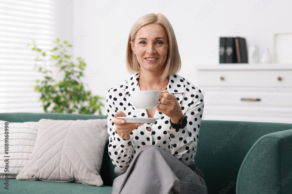Smiling middle aged woman with cup of hot drink on sofa at home Smiling middle aged woman with cup of hot drink on sofa at home