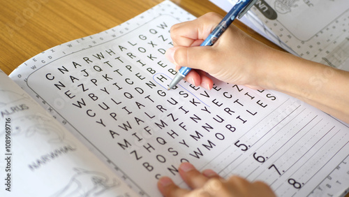 Close up of a kid solving a word search puzzle