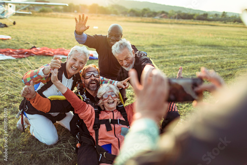 Diverse senior friends taking group photo after skydiving