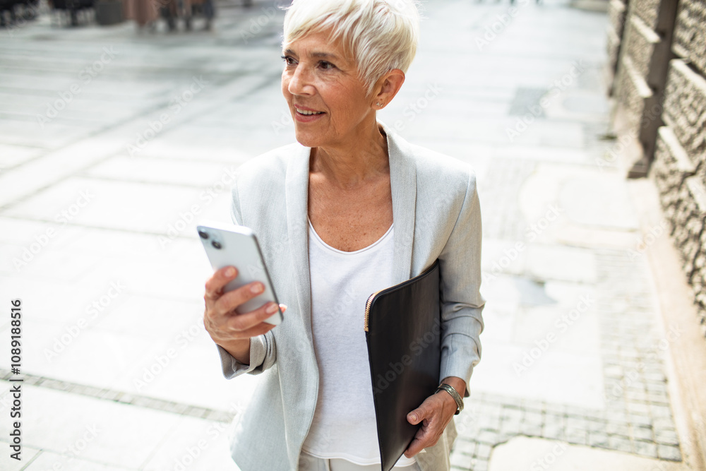 Smiling senior businesswoman using smartphone downtown Smiling senior businesswoman using smartphone downtown