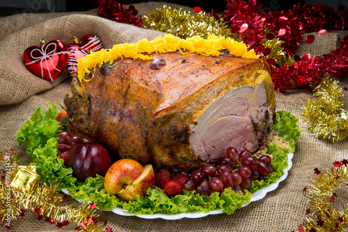 Roastedham on a Christmas dinner table with egg threads, lettuce, apple, fresh grapes and fresh plums photo