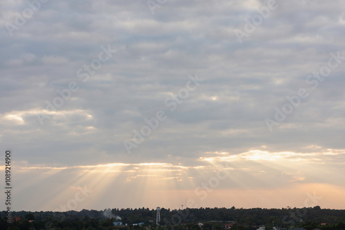 sky filled with clouds during either sunrise or sunset. Sunlight is breaking through the clouds in several places, creating a dramatic effect known as “God rays” or “crepuscular rays.”