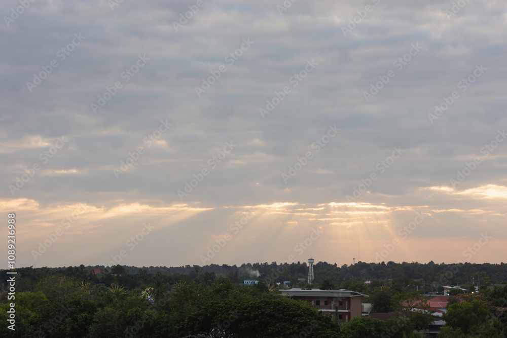 Obraz premium sky filled with clouds during either sunrise or sunset. Sunlight is breaking through the clouds in several places, creating a dramatic effect known as “God rays” or “crepuscular rays.”
