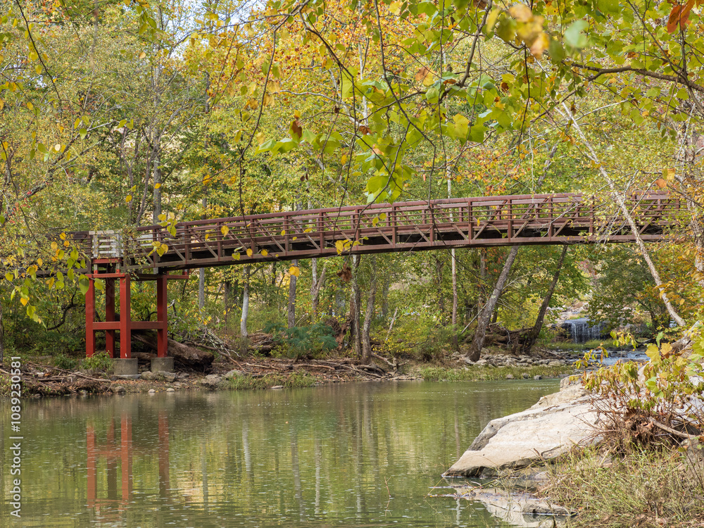 Bridge with a red foundation at Sandstone Falls, New River Gorge National Park, reflecting in the water alongside vibrant autumn foliage Bridge with a red foundation at Sandstone Falls, New River Gorge National Park, reflecting in the water alongside vibrant autumn foliage