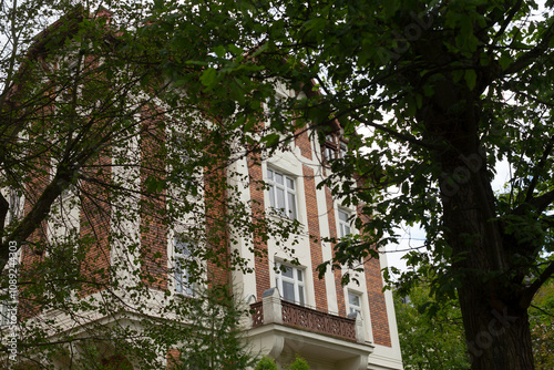 This attractive brick building features large windows and inviting balconies, complemented by lush trees, creating a stunning and serene atmosphere that enhances the propertys appeal