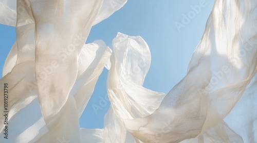 Light white fabric sways gracefully in the wind, beautifully contrasting with the serene backdrop of a bright blue sky.