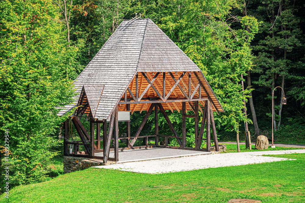 Wooden gazebo with a stage in the forest.