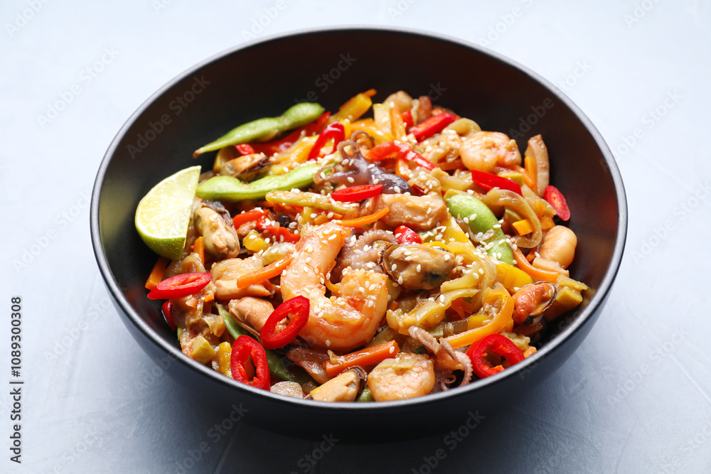 Stir-fry sea food in bowl on light grey table, closeup Stir-fry sea food in bowl on light grey table, closeup