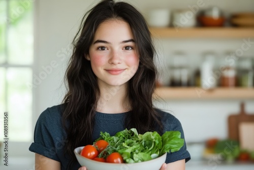 young woman holding a bowl of fresh vegetables in a bright kitchen