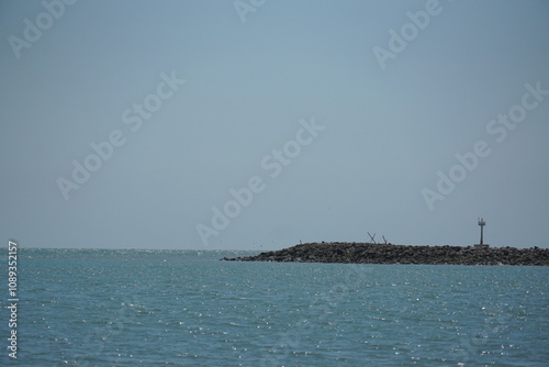 Serene coastal view of a lighthouse on a tranquil day seaside landscape photography calm waters distant perspective nature's beauty