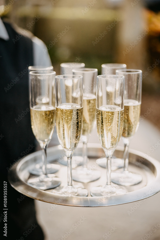 a silver tray with champagne flutes, filled with sparkling champagne, suggesting a celebratory event. a silver tray with champagne flutes, filled with sparkling champagne, suggesting a celebratory event.