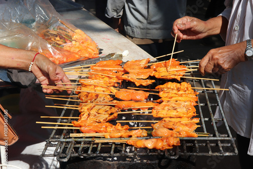 Thai-style grilled pork, Thai street food.person hand-choosing pork grilled for eating.