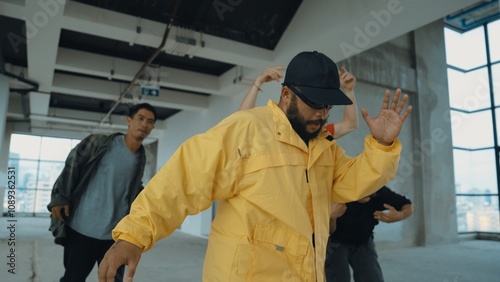 Multicultural hipster group looking at camera while perform break dancing at building with sky scrapper or city view. Street dancer team looking at dancer performance. Outdoor sport 2024. Hiphop.
