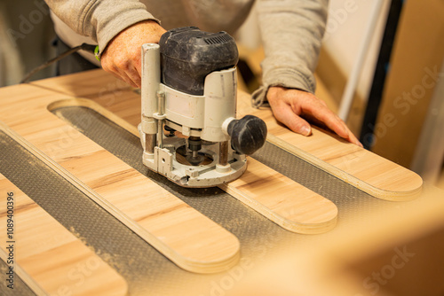 Ouvrier artisan blanc expérimenté en train d'utiliser une défonceuse à bois pour fabriquer un meuble dans son atelier