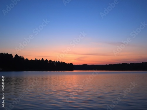 peaceful lake at dusk with silhouetted trees, gentle evening light, serene mood, silhouetted trees