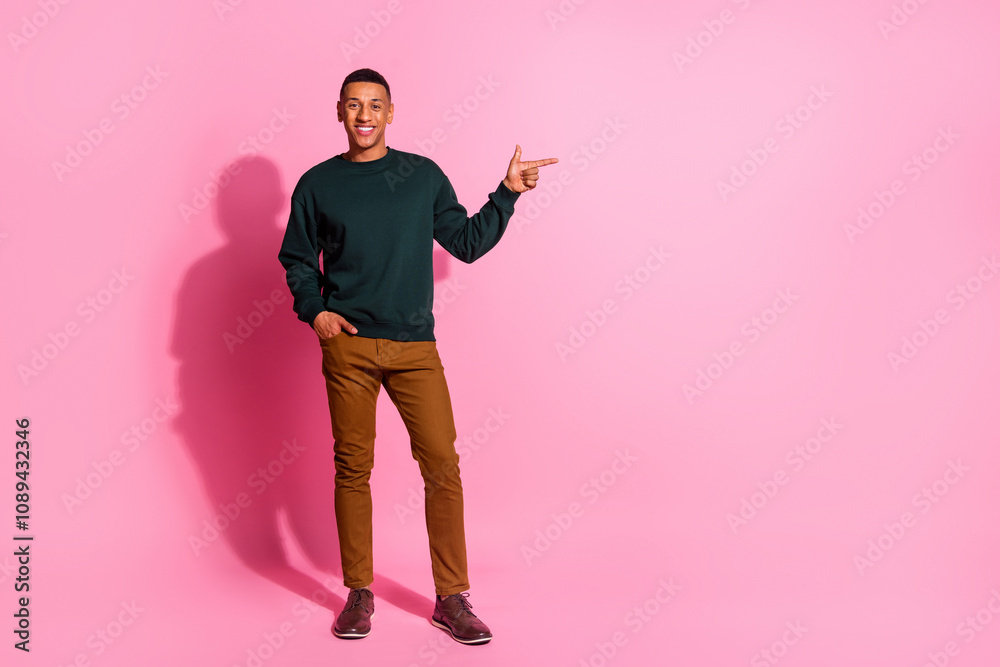 Full length photo of cheerful positive guy dressed pullover pointing emtpy space isolated pink color background Full length photo of cheerful positive guy dressed pullover pointing emtpy space isolated pink color background