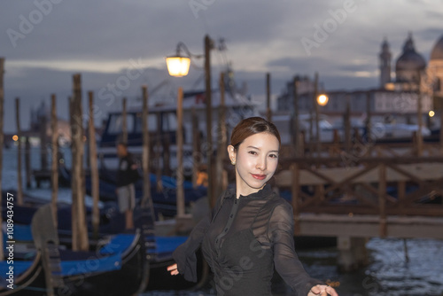 Woman with night view of gondolas, canals and old town background Italy, Venice.