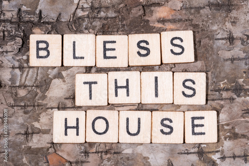 Christian religious background concept. Bless This House written with wooden block letters on natural wood bark background.