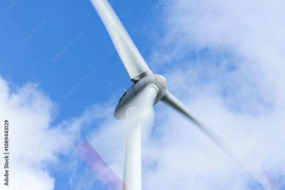 Windrad in Bewegung mit Bewegungsunschärfe vor blauem Himmel mit Wolken Windrad in Bewegung mit Bewegungsunschärfe vor blauem Himmel mit Wolken