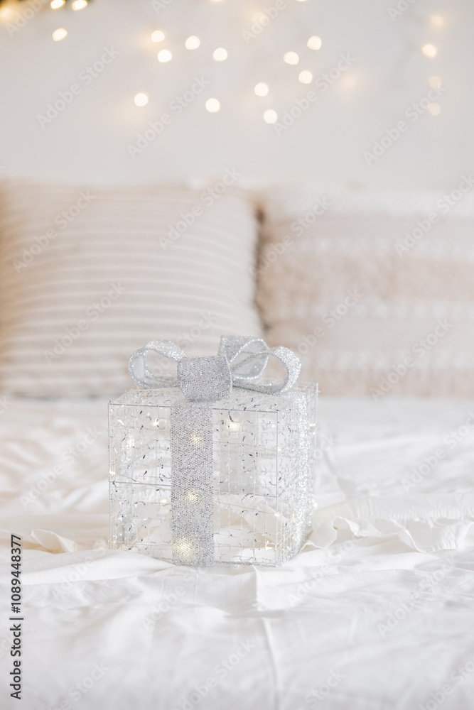 A beautiful transparent gift box with silver ribbon on a cozy bed scene