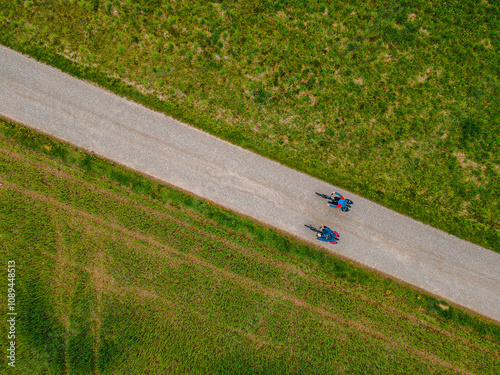Zwei Radfahrer nebeneinander auf einem Radweg neben grüner Wiese