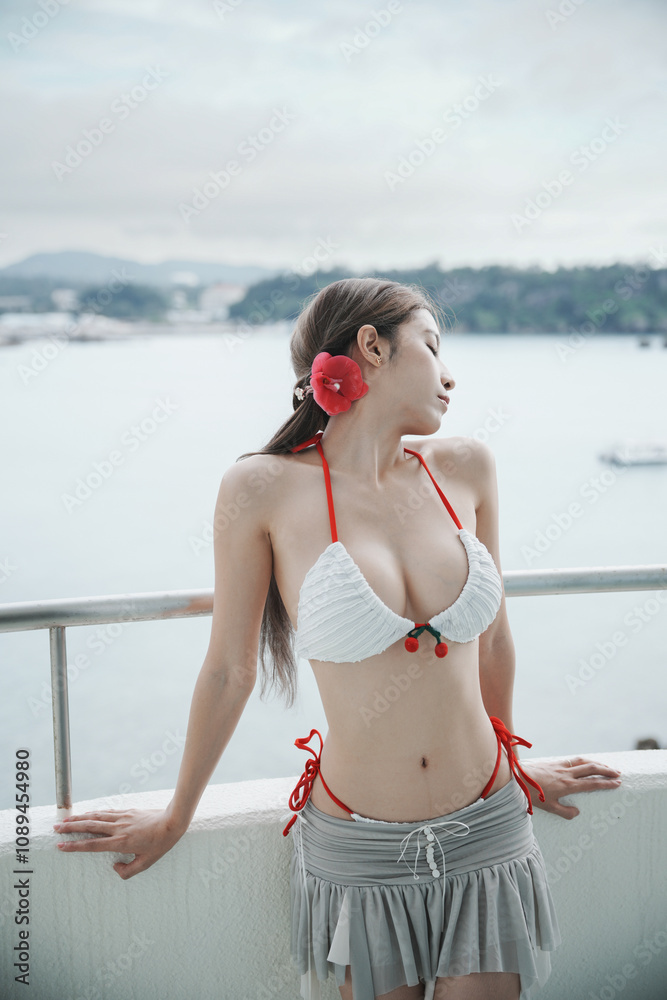 Naklejka premium Woman wearing bikini enjoy ocean view from beachfront balcony tropical resort.