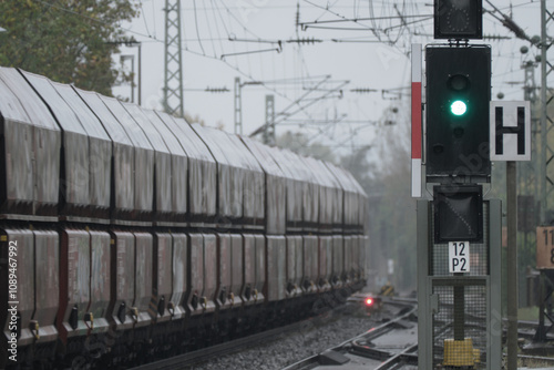 Regenfoto von Güterzug mit Kohlewaggons und Signal auf grün - Stockfoto