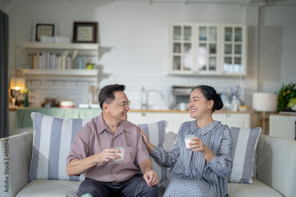 An elderly couple enjoys a peaceful moment at home, sharing smiles and drinks. The warm and cozy atmosphere emphasizes their deep connection, happiness, and the comfort of spending time together. An elderly couple enjoys a peaceful moment at home, sharing smiles and drinks. The warm and cozy atmosphere emphasizes their deep connection, happiness, and the comfort of spending time together.
