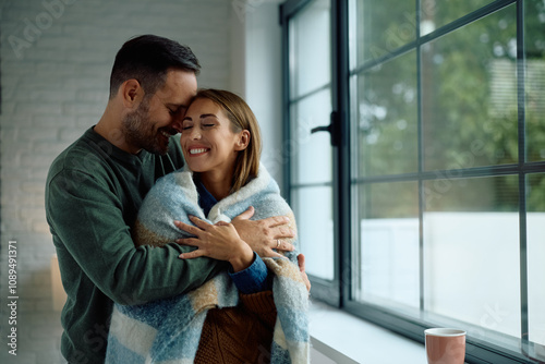 Canvas-taulu Embraced couple enjoying in cosiness of their home during cold winter day