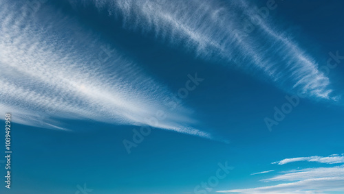 Feathery clouds sweep gracefully through a clear blue sky photo