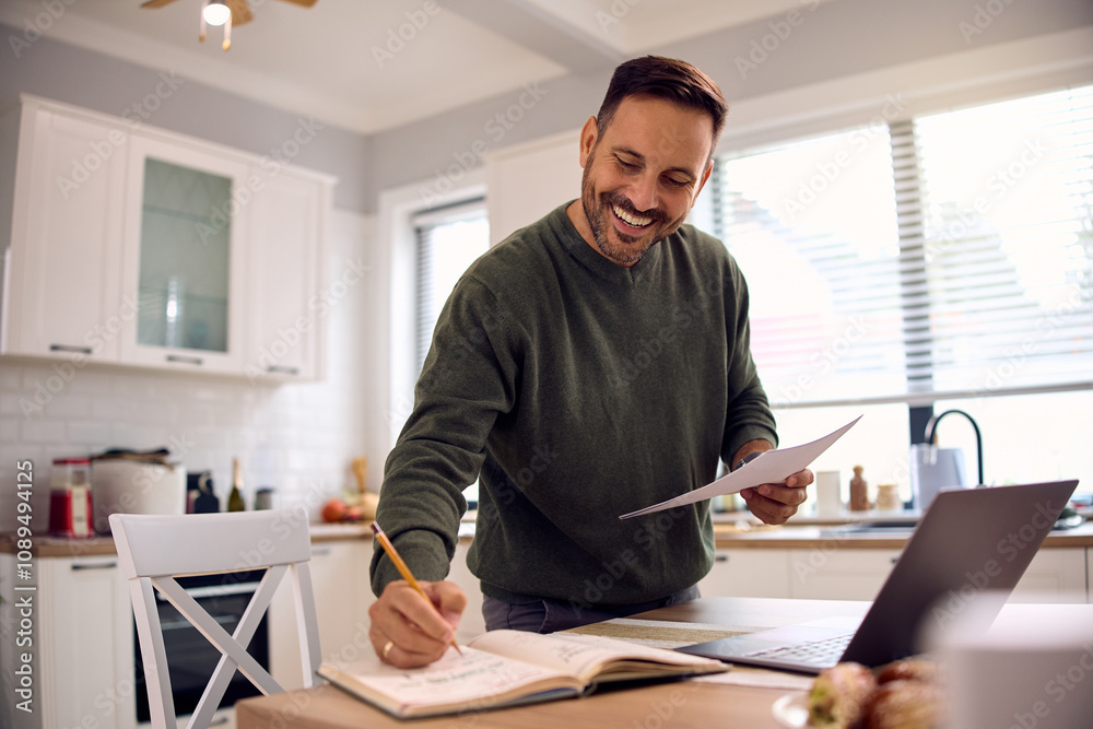 Happy entrepreneur taking notes while working on business reports at home Happy entrepreneur taking notes while working on business reports at home