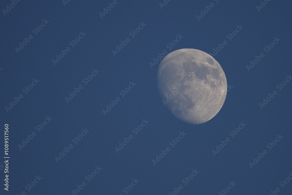 Close-up of the moon against a deep blue sky, showcasing its craters and details Close-up of the moon against a deep blue sky, showcasing its craters and details