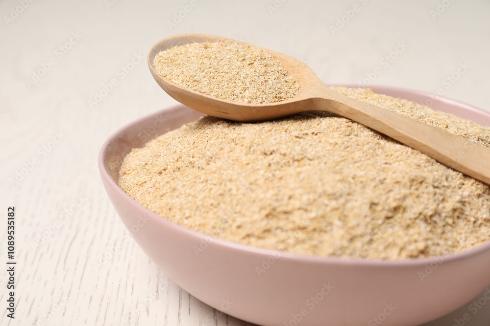 Oat bran in bowl and spoon on light wooden table, closeup Oat bran in bowl and spoon on light wooden table, closeup