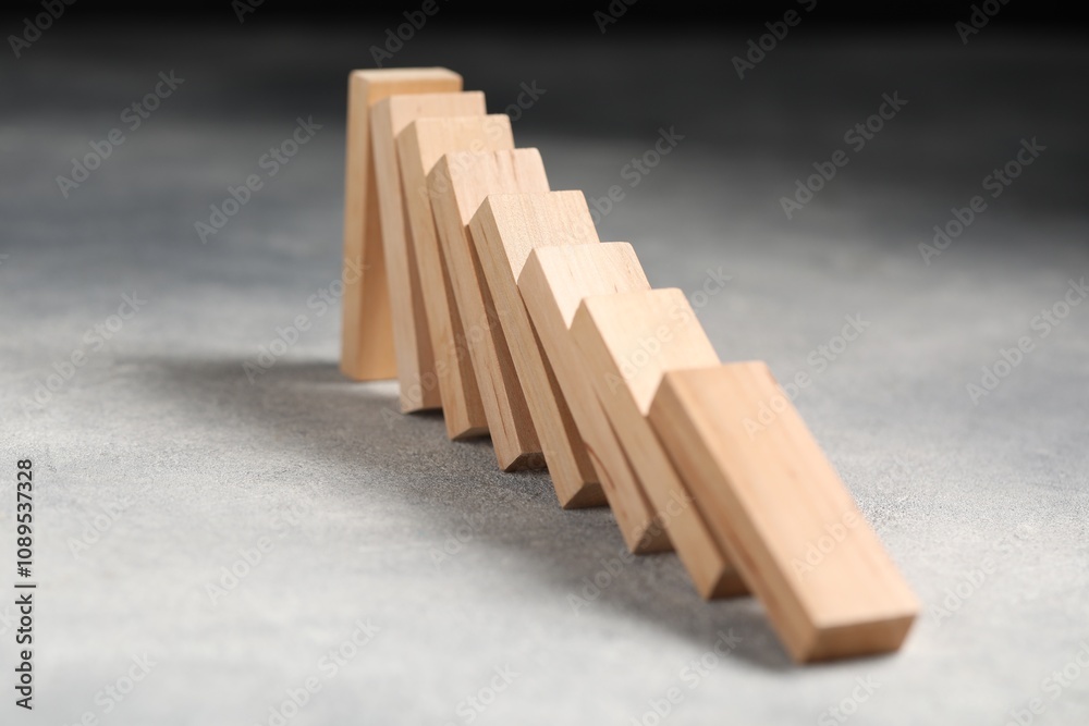 Domino effect. Wooden blocks falling on grey table, closeup Domino effect. Wooden blocks falling on grey table, closeup