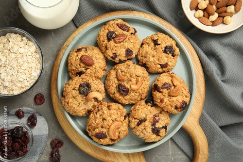 Delicious oatmeal cookies with raisins and nuts on grey table, flat lay photo