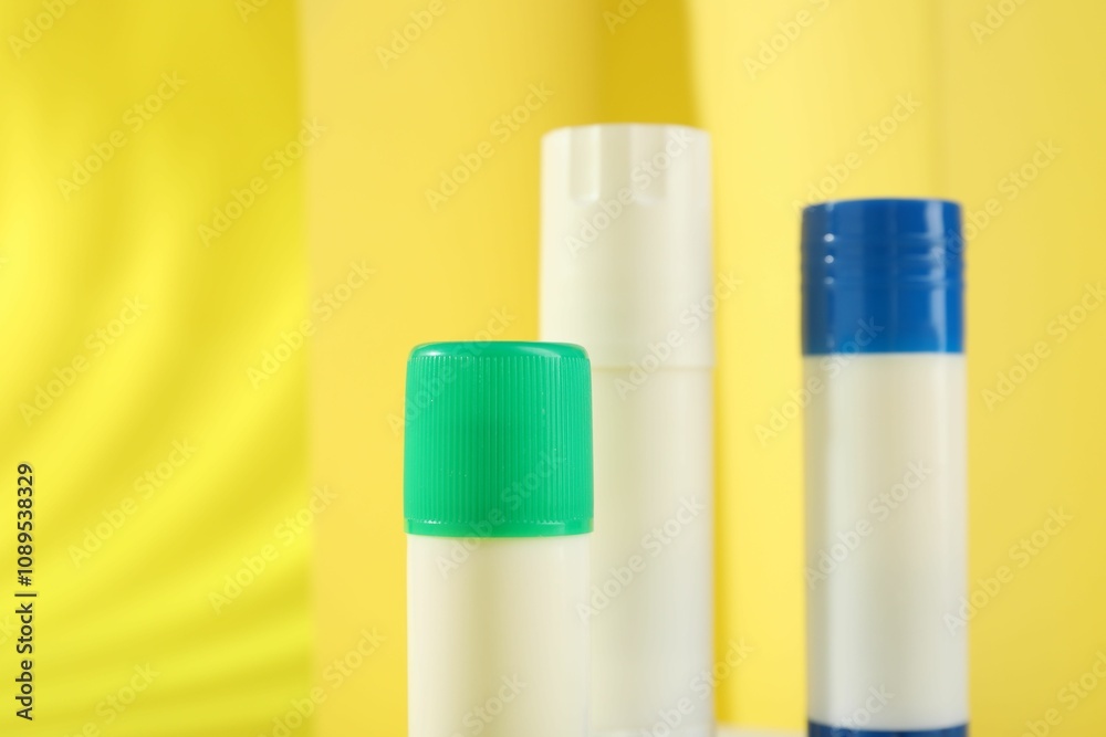 Sticks of glue on yellow background, closeup. Space for text Sticks of glue on yellow background, closeup. Space for text
