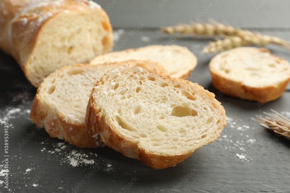 Pieces of fresh baguette with flour and spikes on grey wooden table, closeup Pieces of fresh baguette with flour and spikes on grey wooden table, closeup