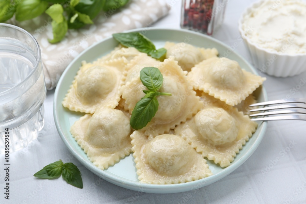 Delicious ravioli with cheese and basil served on white tiled table, closeup Delicious ravioli with cheese and basil served on white tiled table, closeup