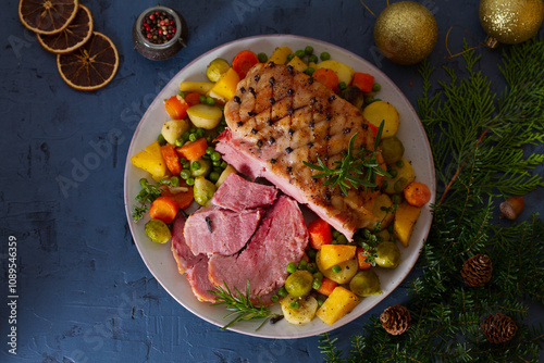 Clove baked ham with potatoes, carrots, turnip and brussel sprouts. Christmas decorations. New Year dinner table. View from above, top studio shot
