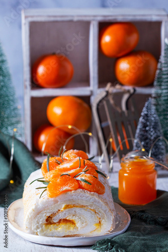 Obraz na płótnie Meringue roll filled with mascarpone, cream and tangerine jam, decorative Christmas trees and tangerines. w salonie