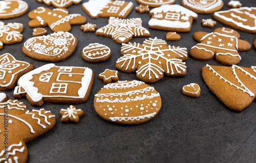 Christmas gingerbread cookies with icing on a gray background in the shape of a house and a gingerbread man, a tree and balls, stars and snowflakes and hearts.