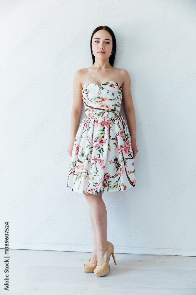 Beautiful brunette woman in summer dress with flowers on white background Beautiful brunette woman in summer dress with flowers on white background